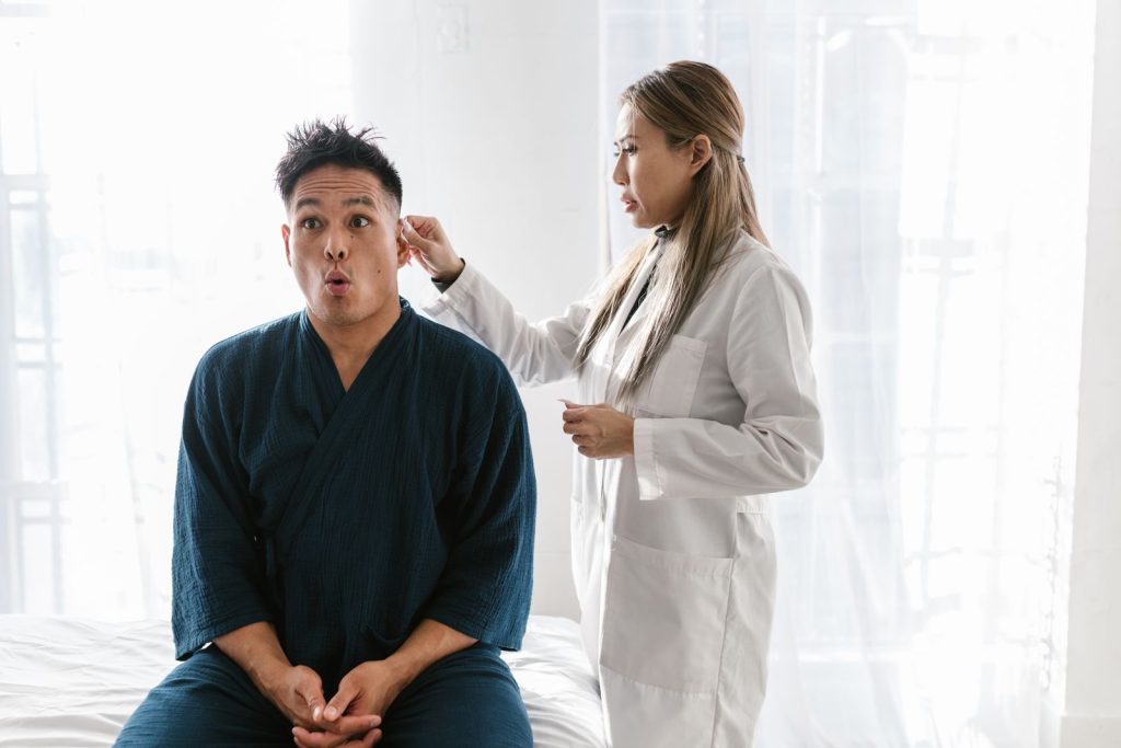 Ärztin untersucht Ohr und Rachen eines Patienten